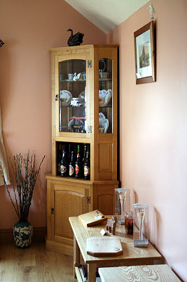 corner display cabinet with glass door in oak alongside smaller items